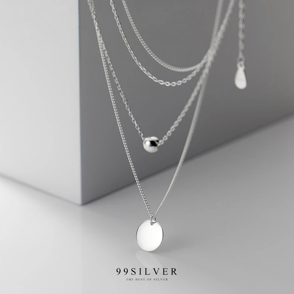 จี้เงินแผ่นกลมคล้องอยู่ในสร้อยคอดีไซน์แบบสองชั้นพร้อมชาร์มกลมน่ารัก
