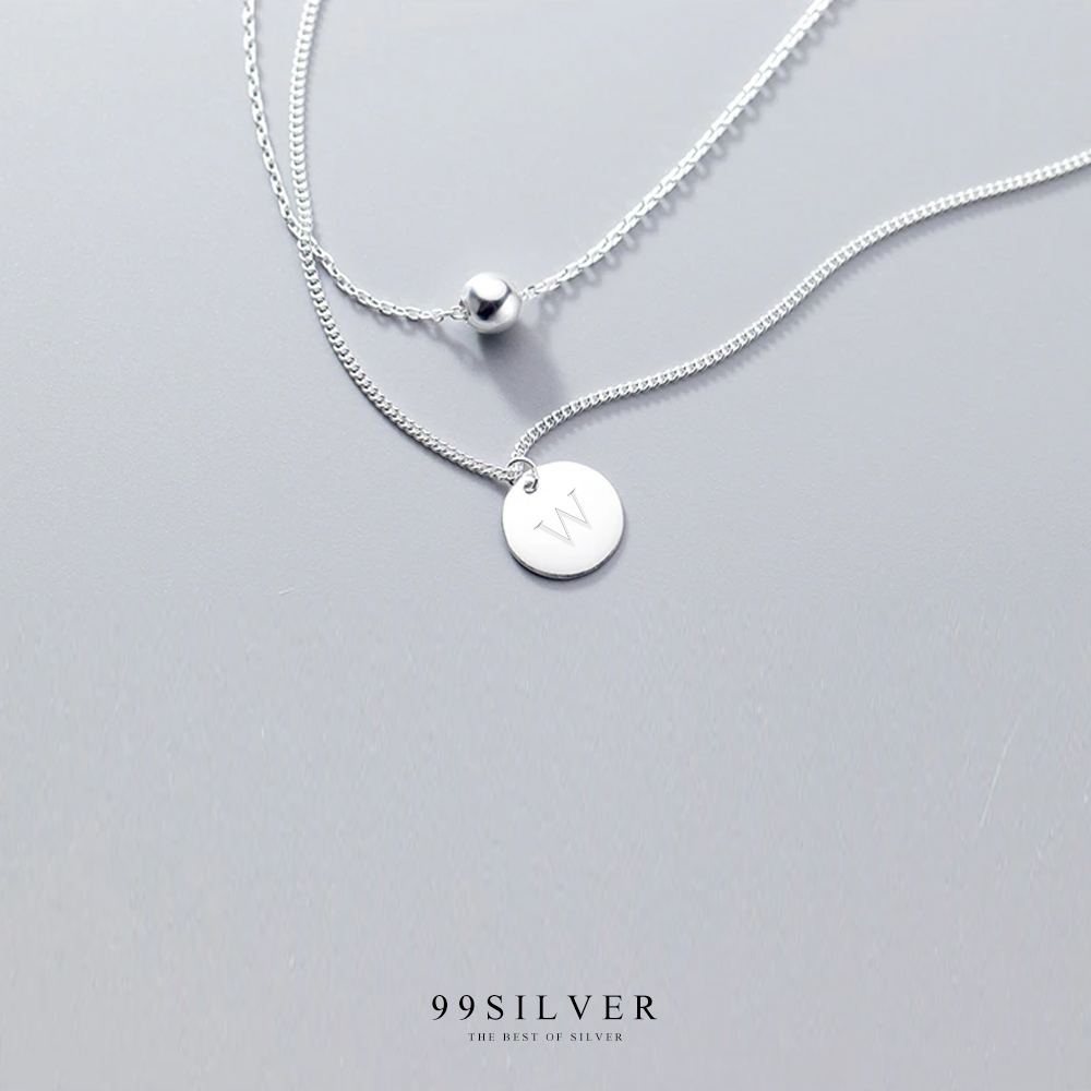 จี้เงินแผ่นกลมคล้องอยู่ในสร้อยคอดีไซน์แบบสองชั้นพร้อมชาร์มกลมน่ารัก