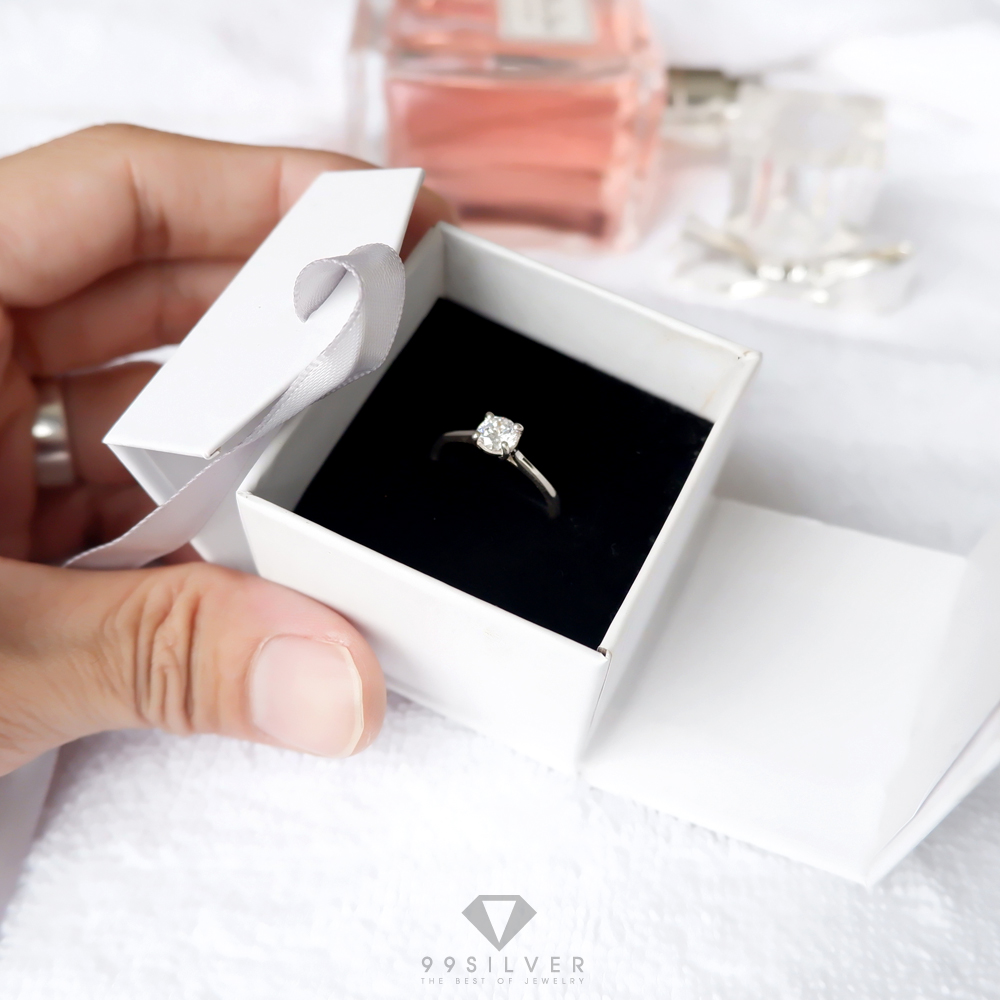 กล่องใส่แหวนสีขาวสี่เหลี่ยม  มีริบบิ้นผูกโบว์สำหรับยึดฝา ข้างในบุด้วยสปั้นช์นิ่มสีดำ