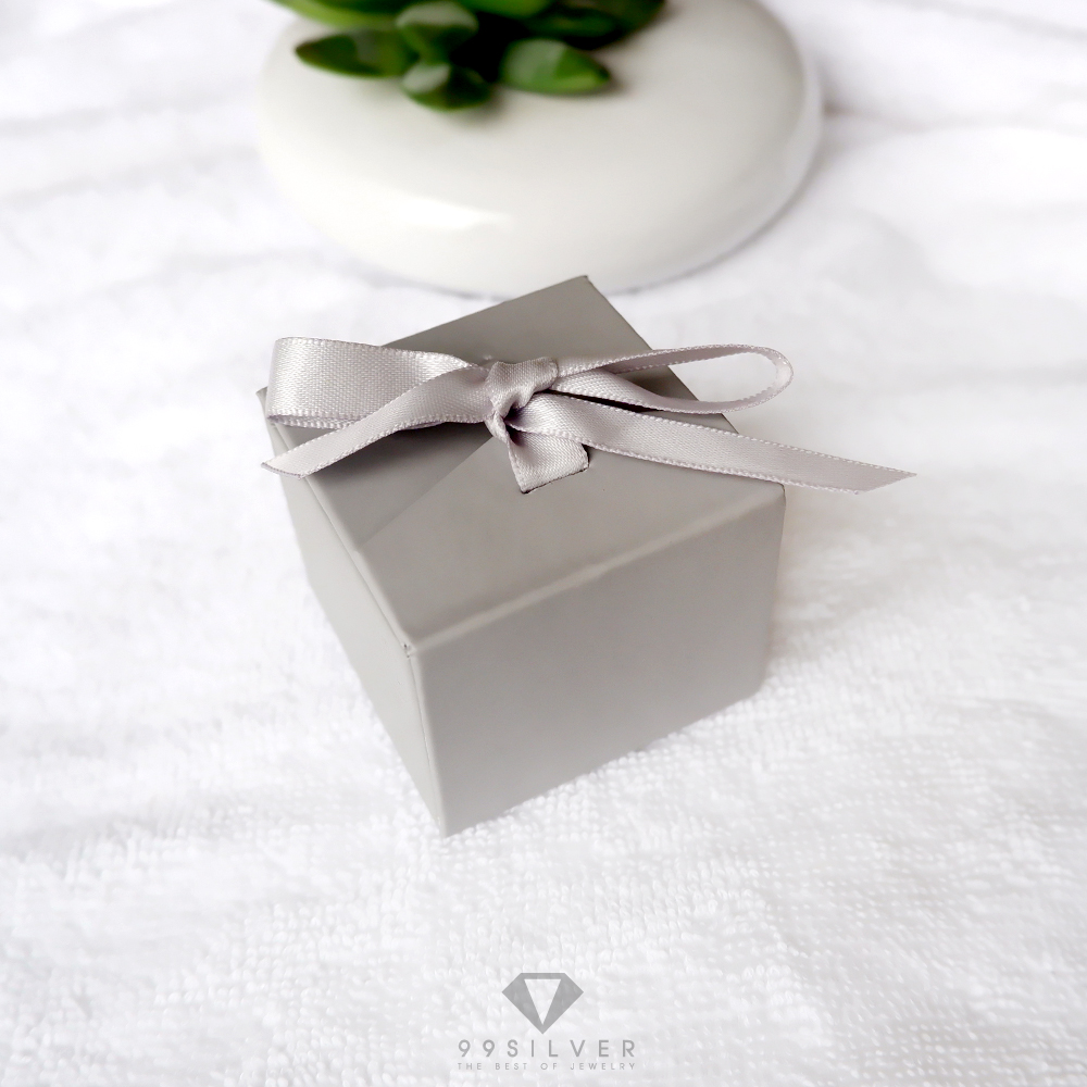 กล่องใส่แหวนสีเทาสี่เหลี่ยม มีริบบิ้นผูกโบว์สำหรับยึดฝา ข้างในบุด้วยสปั้นช์นิ่มสีน้ำตาลเข้ม