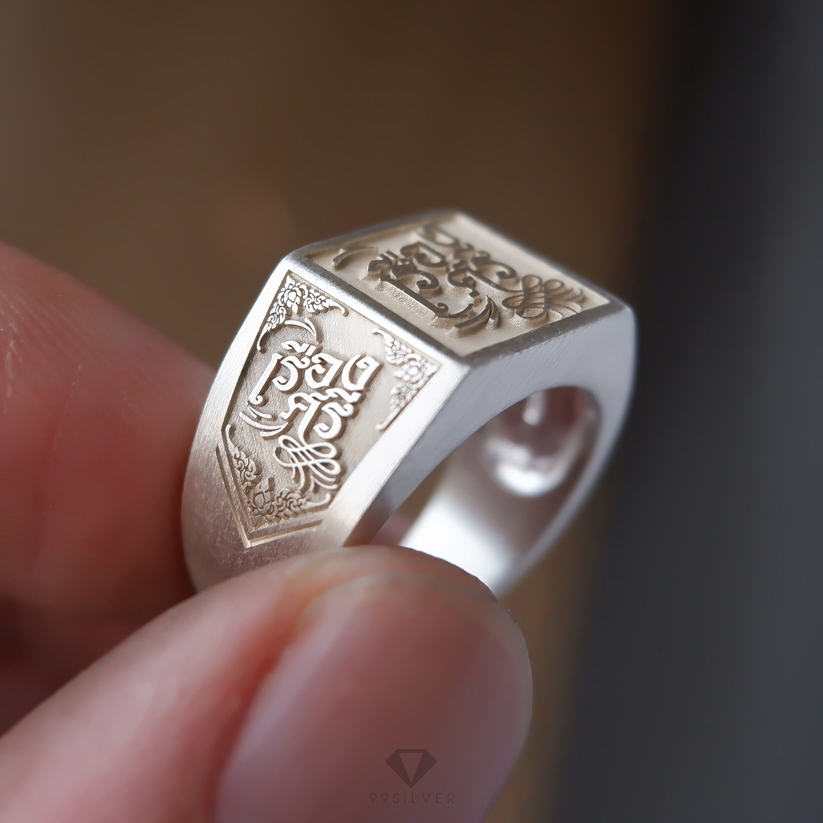 แหวนนามสกุลหน้าเหลี่ยม 11 มิลลิเมตร เนื้อตันแกะลายออกแบบอักษร พื้นหลังพ่นทราย