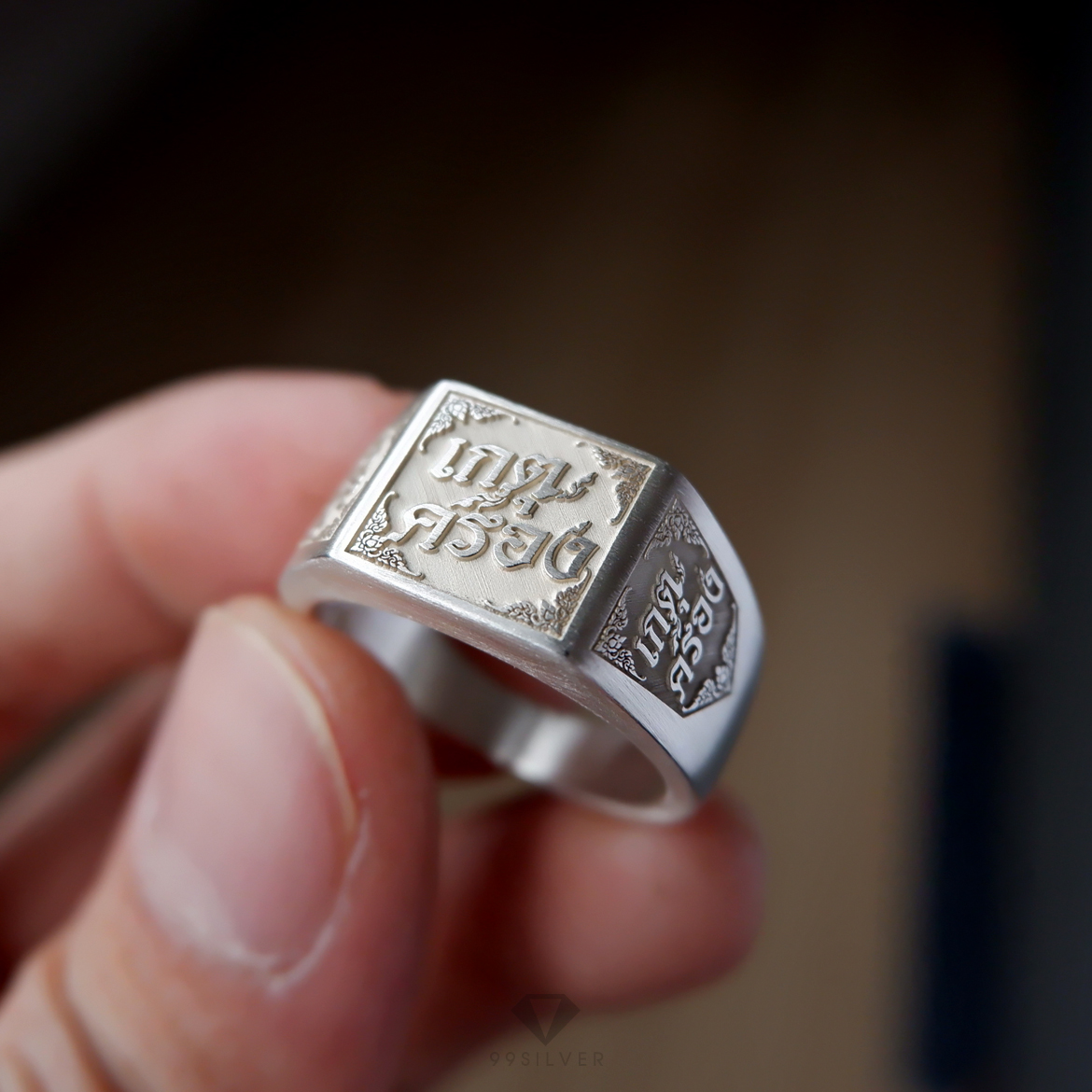 แหวนนามสกุลหน้าเหลี่ยม 11 มิลลิเมตร เนื้อตันแกะลายออกแบบอักษร พื้นหลังพ่นทราย
